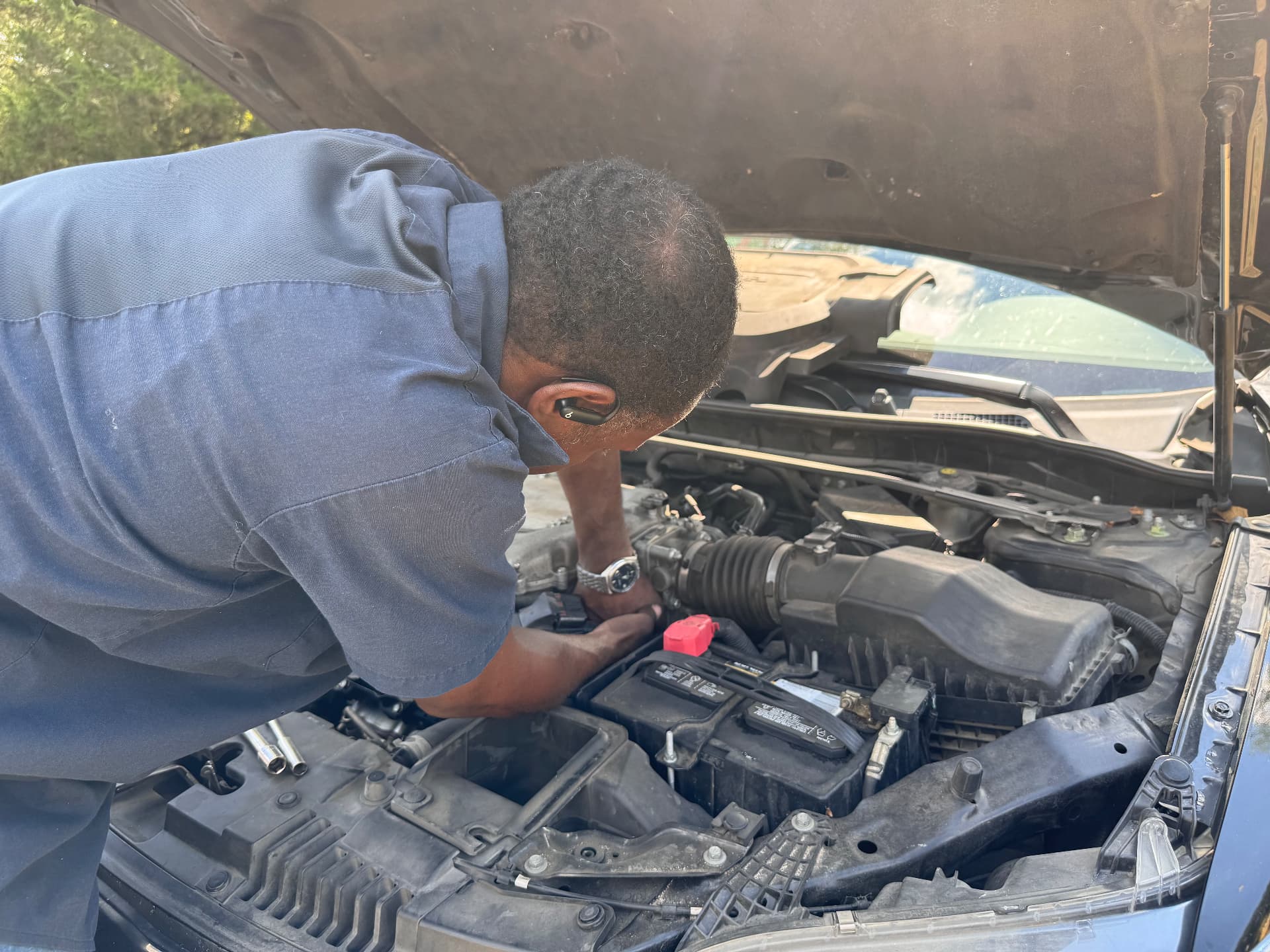 Brian leaning into an open engine bay working on a car